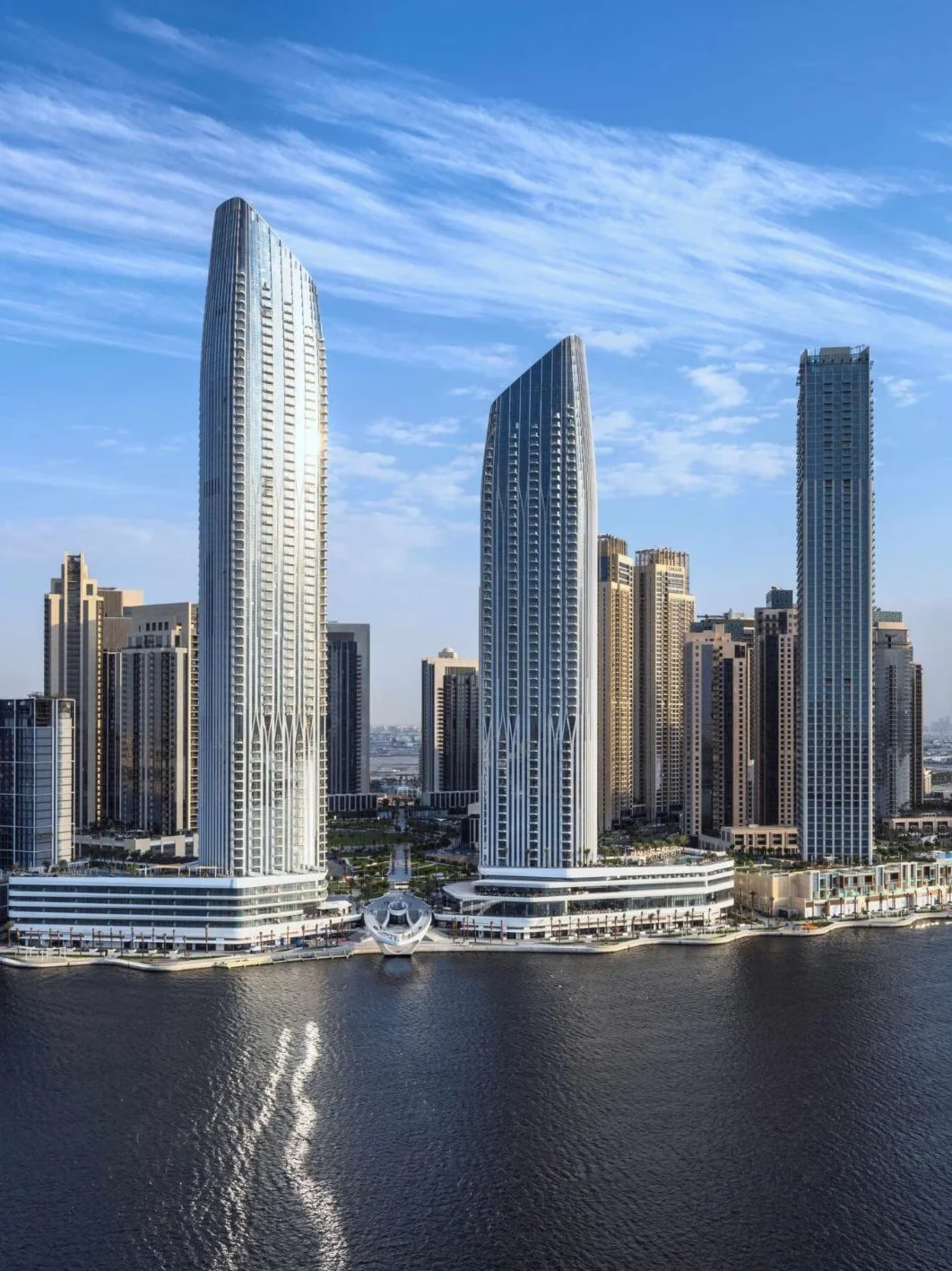 Waterfront high-rise towers in Dubai under a blue sky